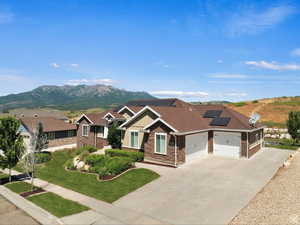Craftsman-style home with roof mounted solar panels, concrete driveway, board and batten siding, a mountain view, and an attached garage