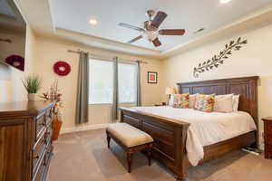 Bedroom featuring light colored carpet, a tray ceiling, a ceiling fan, and recessed lighting