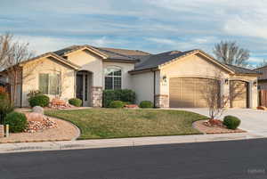 View of front of house with an attached garage, driveway, stucco siding, and a front yard