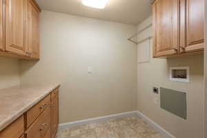 Laundry room with cabinet space, hookup for an electric dryer, stone finish floors, and washer hookup