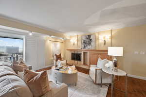 Living area with a fireplace, ornamental molding, and wood finished floors