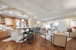 Living area featuring dark wood-type flooring, track lighting, and ornamental molding