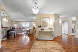 Foyer entrance featuring ornamental molding, dark wood-style floors, and a chandelier