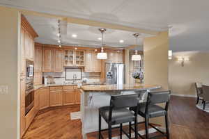 Kitchen featuring a kitchen bar, stainless steel appliances, glass insert cabinets, decorative backsplash, and light stone countertops