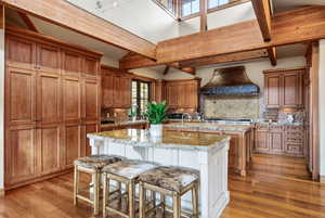 Kitchen featuring light stone countertops, two tone color scheme, a kitchen bar, light wood-style flooring, and decorative backsplash