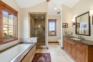 Bathroom with vanity, a stall shower, a garden tub, light tile patterned flooring, and lofted ceiling