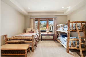 Bedroom featuring light colored carpet, recessed lighting, and a raised ceiling