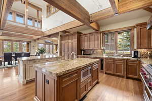 Kitchen with wood finish cabinets, stainless steel appliances, light wood-style floors, and tasteful backsplash