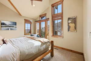 Carpeted bedroom with a ceiling fan, vaulted ceiling, and access to outside