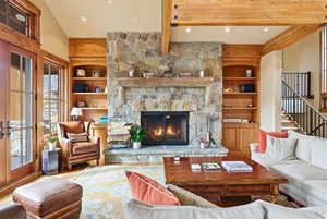 Living area with built in shelves, a stone fireplace, wood finished floors, and recessed lighting