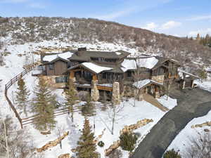 Snow covered property with a balcony, board and batten siding, and a chimney