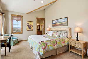 Bedroom featuring carpet floors, vaulted ceiling, and connected bathroom