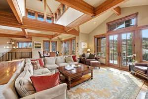 Living room featuring hardwood / wood-style floors, french doors, suspended lighting, and vaulted ceiling