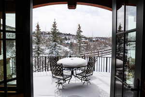 Snow covered back of property featuring outdoor dining space