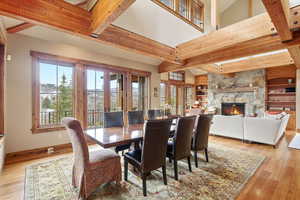 Dining room with plenty of natural light, light wood-style flooring, french doors, and a stone fireplace
