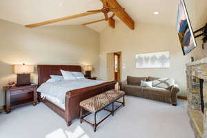 Bedroom featuring ceiling fan, a stone fireplace, and light carpet