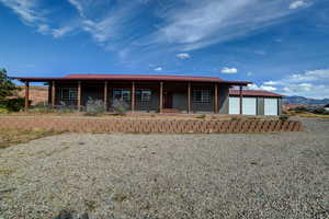 View of front of house with covered porch, a mountain view, a metal roof, an outbuilding, and driveway