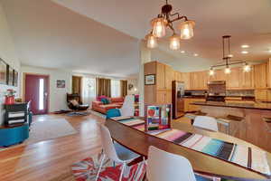 Dining area featuring vaulted ceiling, light wood-style floors, and a chandelier