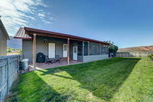 Back of house with a fenced backyard, a sunroom, a mountain view, and a patio