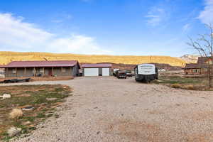 View of front of property featuring driveway, a mountain view, a detached garage, and covered porch