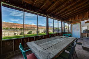 Sunroom with a mountain view, vaulted ceiling with beams, and outdoor dining area