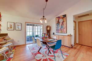 Dining space featuring vaulted ceiling, light wood-style flooring, and suspended lighting