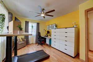 Home office with light wood-type flooring and a ceiling fan
