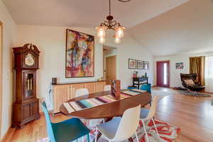 Dining space with suspended lighting, light wood-type flooring, and vaulted ceiling