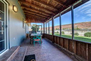 Sunroom / solarium with outdoor dining space, vaulted ceiling with beams, and a mountain view