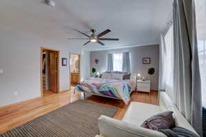 Bedroom featuring light wood-type flooring, ceiling fan, and connected bathroom