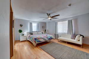 Bedroom with light wood-type flooring, ceiling fan, and a textured ceiling