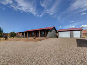Ranch-style home featuring covered porch, an outbuilding, a garage, and gravel driveway