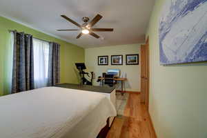 Bedroom featuring a desk, light wood-type flooring, and ceiling fan