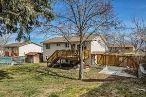 Back of house with a storage unit, a fenced backyard, a wooden deck, a gate, and a swimming pool