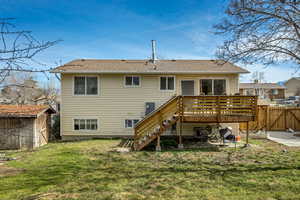 Back of house with a wooden deck, a gate, and a shed