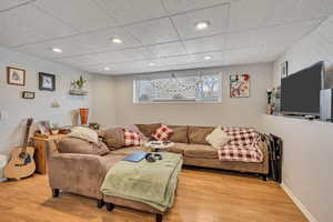Living area featuring light wood-style floors, recessed lighting, and a paneled ceiling