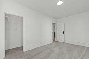 Unfurnished bedroom featuring light carpet and a closet