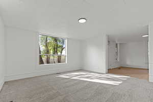 Unfurnished room featuring light carpet and baseboards