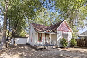 View of front of home with a porch, an outdoor structure, a shingled roof, and a chimney