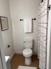 Bathroom with a shower with shower curtain, light wood-style flooring, and a textured wall