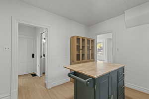 Kitchen with wooden counters, light wood-type flooring, a kitchen island, and glass fronted cabinets