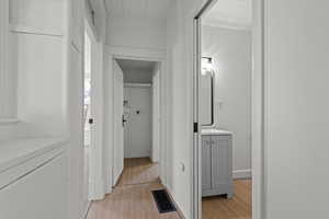 Hall with light wood finished floors and washer / clothes dryer