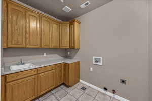 Laundry room with gas dryer hookup, hookup for a washing machine, cabinet space, light tile patterned flooring, and electric dryer hookup