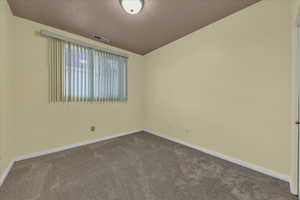 Unfurnished room with dark colored carpet and a textured ceiling