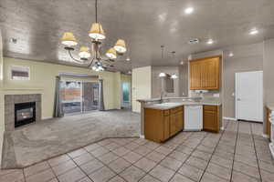Kitchen featuring a textured ceiling, open floor plan, a peninsula, light countertops, and light carpet