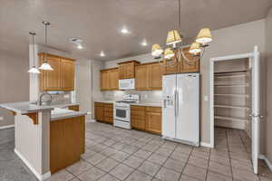 Kitchen featuring white appliances, light countertops, a peninsula, a kitchen bar, and light tile patterned floors