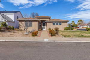 View of front of home featuring stucco siding, a tile roof, and a front yard