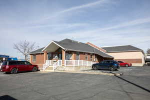 Single story home with brick siding, roof with shingles, and uncovered parking