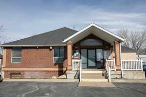 View of front of property featuring brick siding and roof with shingles