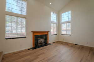 Unfurnished living room with light wood-type flooring, a high ceiling, a premium fireplace, and recessed lighting